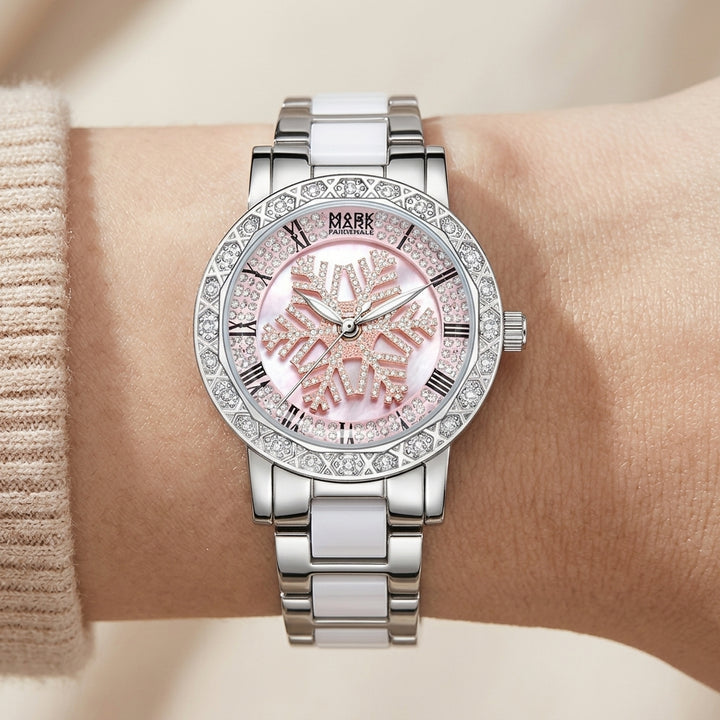 Silver watch with pink face on a wrist against a neutral background