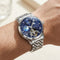 Silver wristwatch with a blue face on a person's wrist against a neutral background
