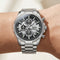 Silver wristwatch with a detailed face on a wrist against a neutral background