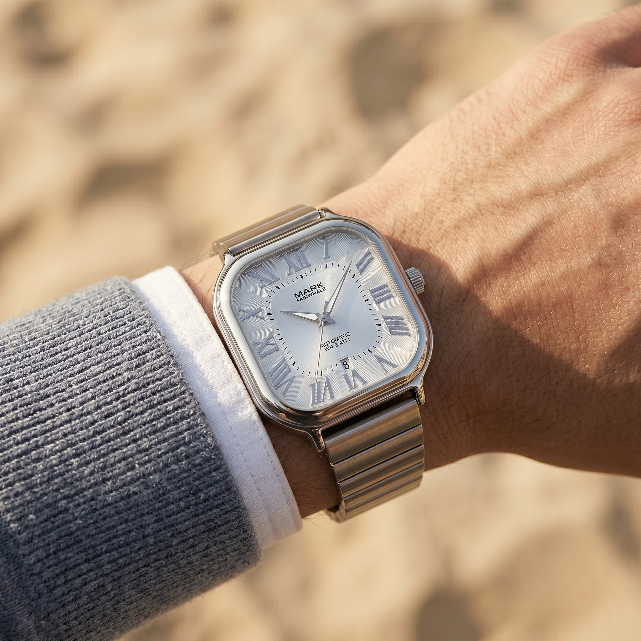 Silver wristwatch with a textured strap on a blurred natural background