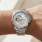 Silver wristwatch with detailed face on a wrist against a neutral background