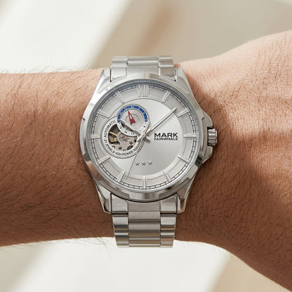 Silver wristwatch with detailed face on a wrist against a neutral background