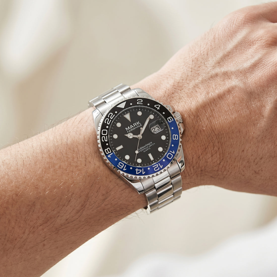 Watch with a black face and blue accents on a wrist against a neutral background