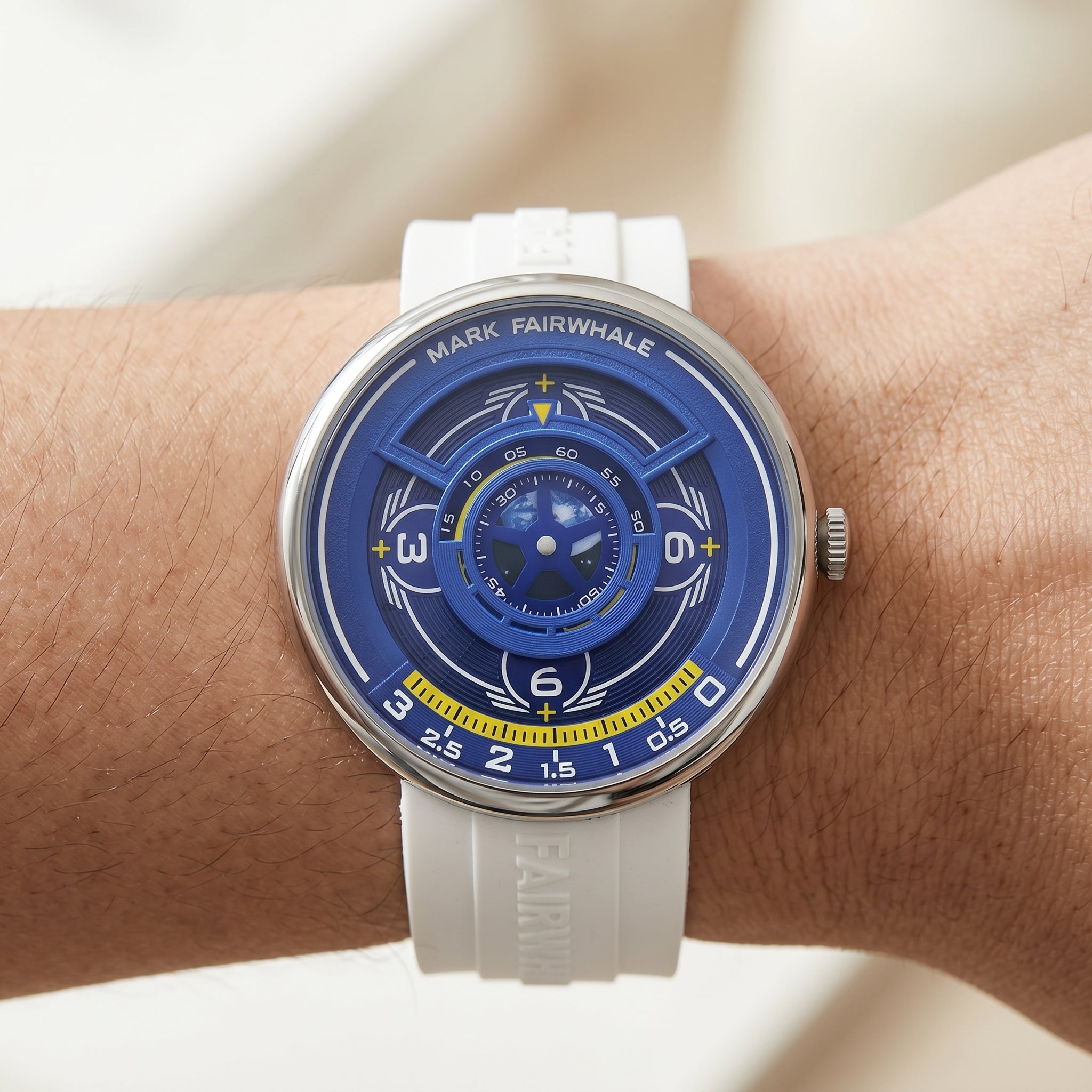 Watch with a blue face and white strap on a wrist against a neutral background