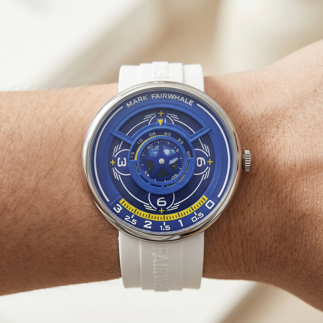 Watch with a blue face and white strap on a wrist against a neutral background
