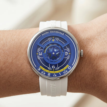 Watch with a blue face and white strap on a wrist against a neutral background