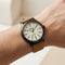 Wrist wearing a watch with a brown leather strap and white face.