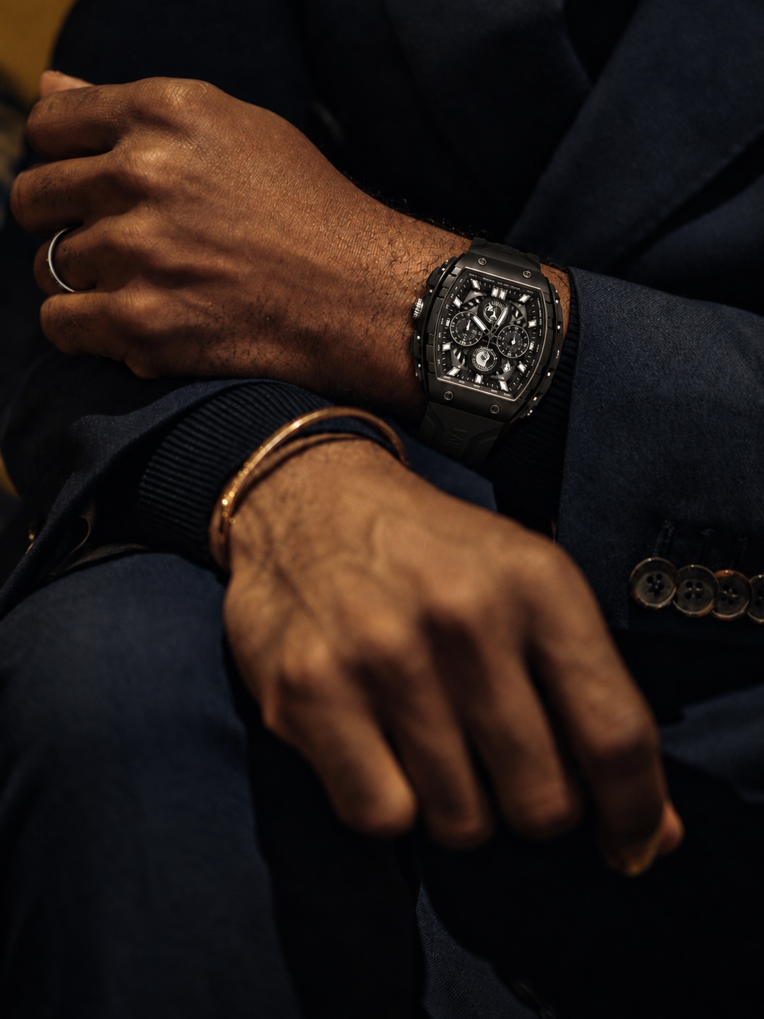 BOLTRON in Black on crossed wrists, worn with a navy suit in warm evening light