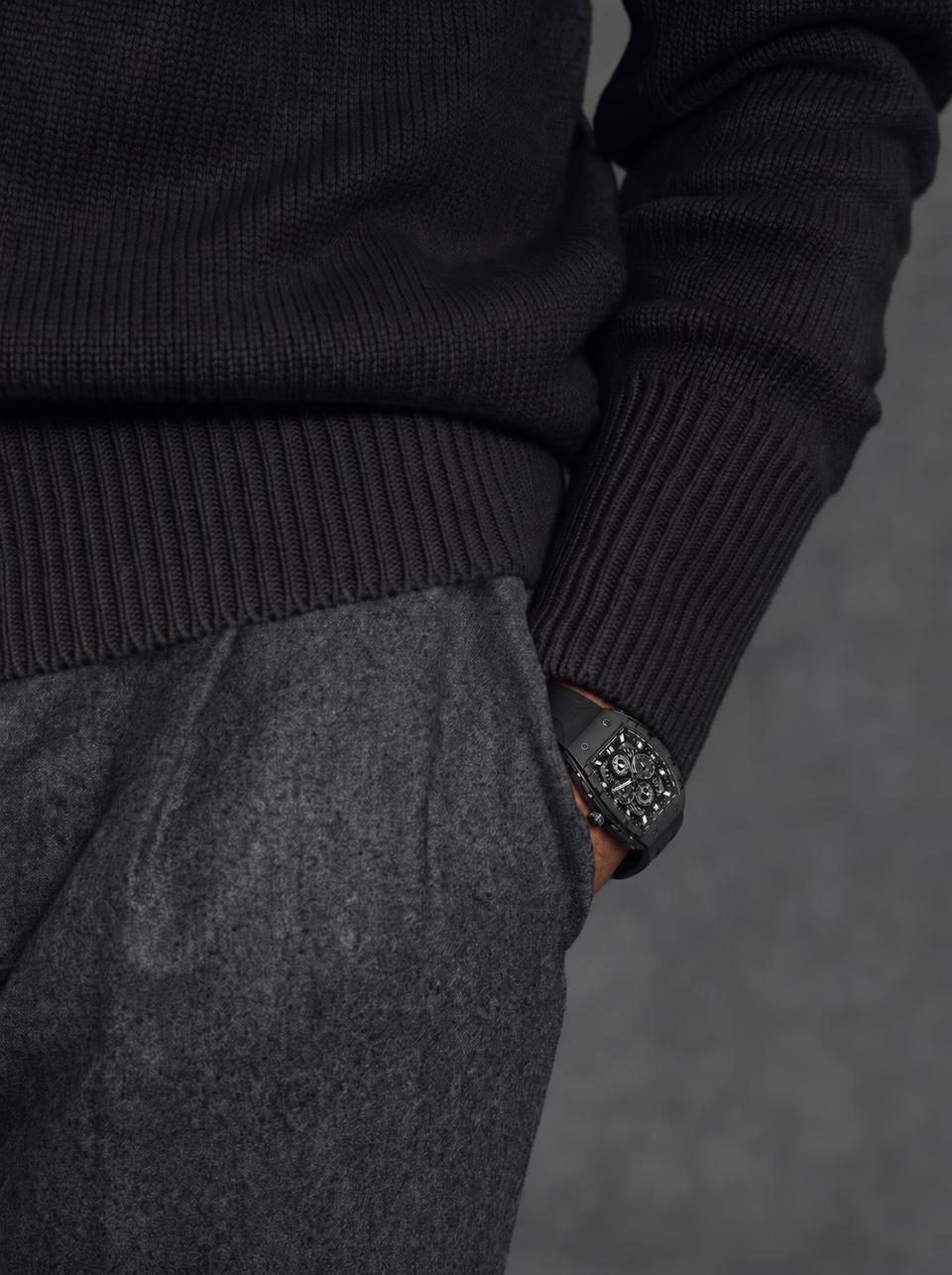 BOLTRON in Black on the wrist of a man in a black knit sweater, hand in the pocket of grey wool trousers
