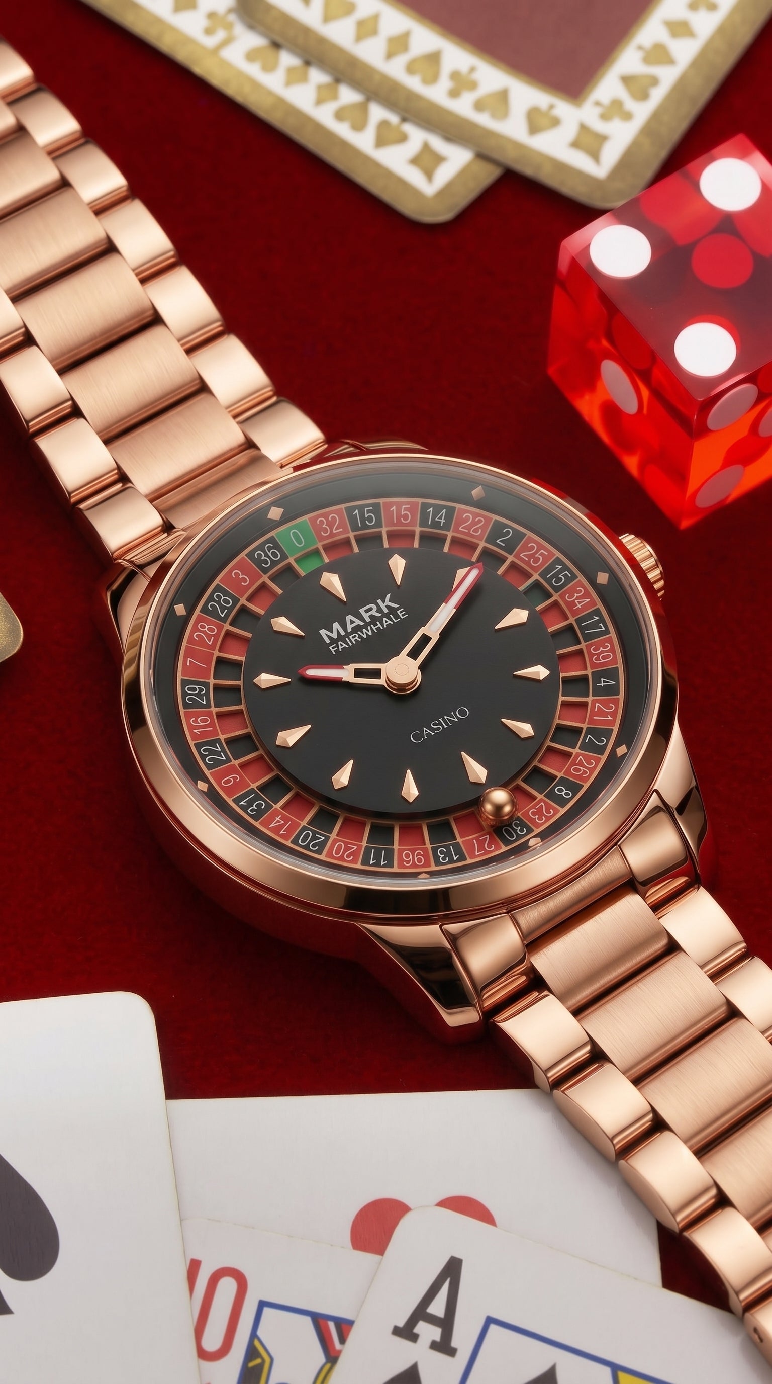 Orologio Mark Fairwhale Roulette in oro rosa accanto a carte da gioco e a un dado rosso